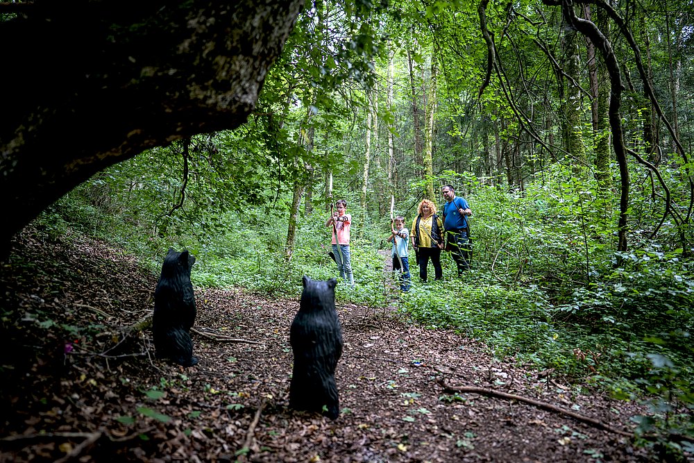 Holzfiguren im Wald zum Bogenschießen vor einer Höhle Holzfiguren im Wald zum Bogenschießen vor einer Höhle