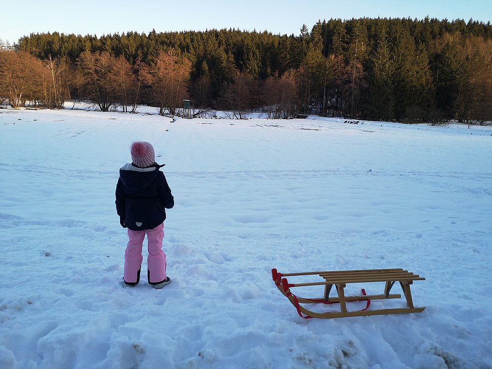 Kind mit Schlitten im Schnee