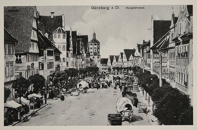 Historische Aufnahme des Günzburger Marktplatzes: Zu sehen ist der Wochenmarkt, auf dem Händler mit Planwagen und Pferden angekommen sind und ihre Waren anbieten. Historische Aufnahme des Günzburger Marktplatzes: Zu sehen ist der Wochenmarkt, auf dem Händler mit Planwagen und Pferden angekommen sind und ihre Waren anbieten.