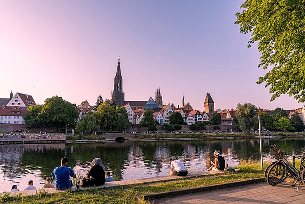 Sonnenuntergang mit Menschen am Ufer sitzend in Neu-Ulm mit Blick auf Ulmer Münster Sonnenuntergang mit Menschen am Ufer sitzend in Neu-Ulm mit Blick auf Ulmer Münster