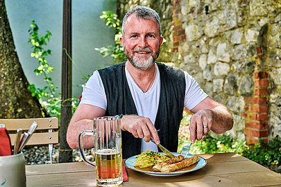 Mann genießt Brotzeit und Bier im Klostergasthof Roggenburg Mann genießt Brotzeit und Bier im Klostergasthof Roggenburg