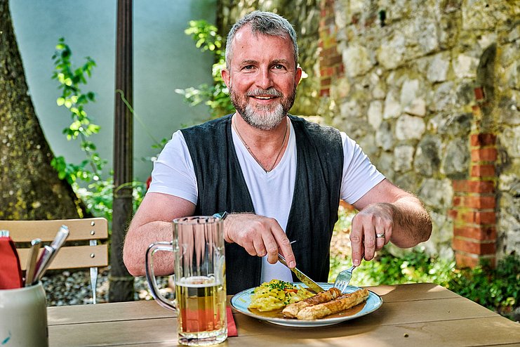 Mann genießt Brotzeit und Bier im Klostergasthof Roggenburg