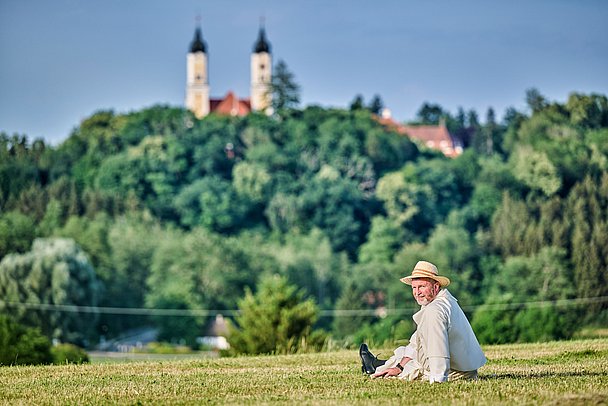 Pater sitzt auf Wiese vor Kloster Roggenburg