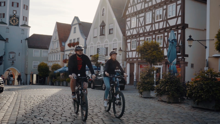Zwei Radfahrer in der Günzburger Altstadt mit alten Häuserfassaden Zwei Radfahrer in der Günzburger Altstadt mit alten Häuserfassaden