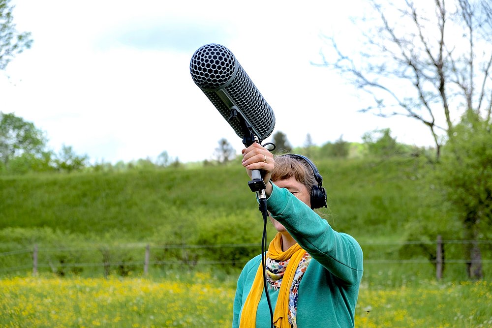 Ein Soundkünstler mit Mikrofon inmitten einer Weidenlandschaft