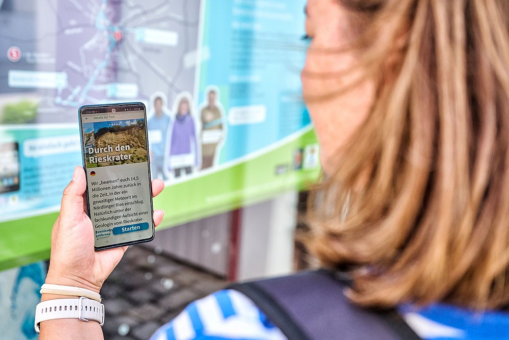 Frau mit Smartphone nimmt an Lauschtour Bayerisch-Schwaben teil