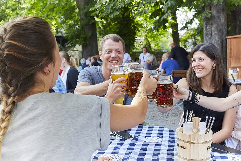Schlössle Biergarten in Neu-Ulm, Gruppe stoßt mit Bier an Schlössle Biergarten in Neu-Ulm, Gruppe stoßt mit Bier an