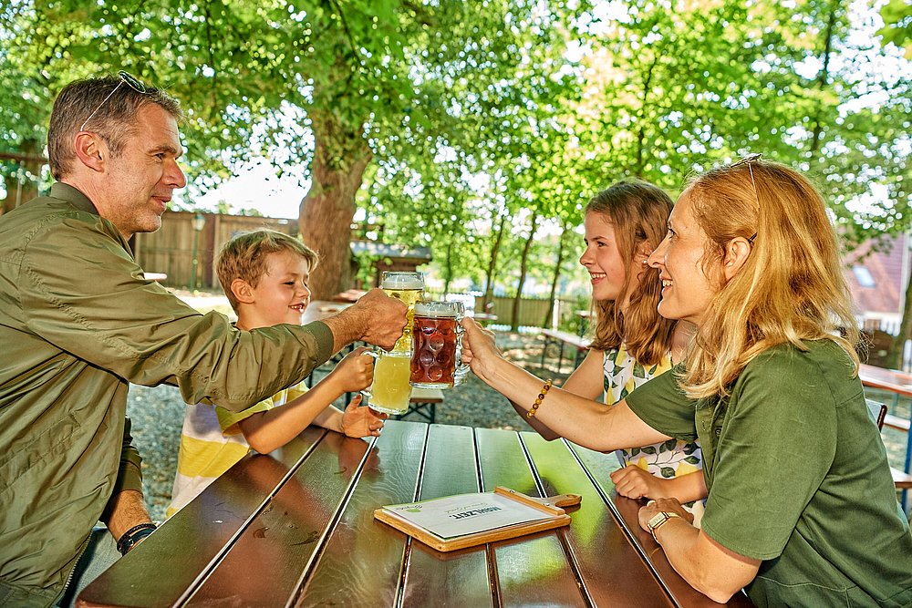 Familie prostet mit Bier im Biergarten Familie prostet mit Bier im Biergarten