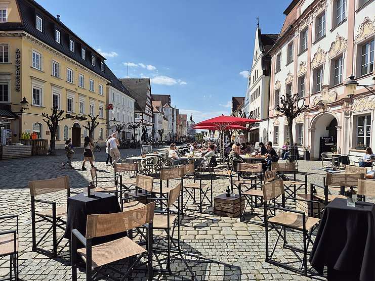 Die Tische und Stühle der Bar ‚Flaneur‘ in Günzburg laden am Abend zu einem Cocktail ein. Von hier aus bietet sich ein fantastischer Blick über den Günzburger Marktplatz.