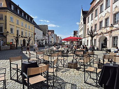 Die Tische und Stühle der Bar ‚Flaneur‘ in Günzburg laden am Abend zu einem Cocktail ein. Von hier aus bietet sich ein fantastischer Blick über den Günzburger Marktplatz.