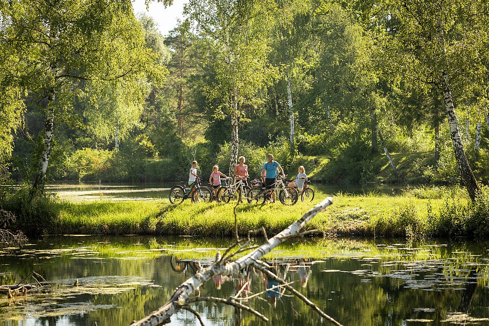 Fahrradfahrer am begrünten Ufer der Topfletseen bei Günzburg Fahrradfahrer am begrünten Ufer der Topfletseen bei Günzburg
