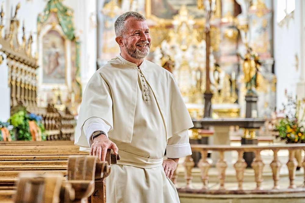 Pater Ulrich zwischen Kirchenbänken in der Klosterkirche Roggenburg Pater Ulrich zwischen Kirchenbänken in der Klosterkirche Roggenburg